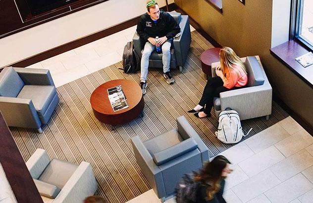 Four students walking in Adams Hall lobby, picture taken from second floor down